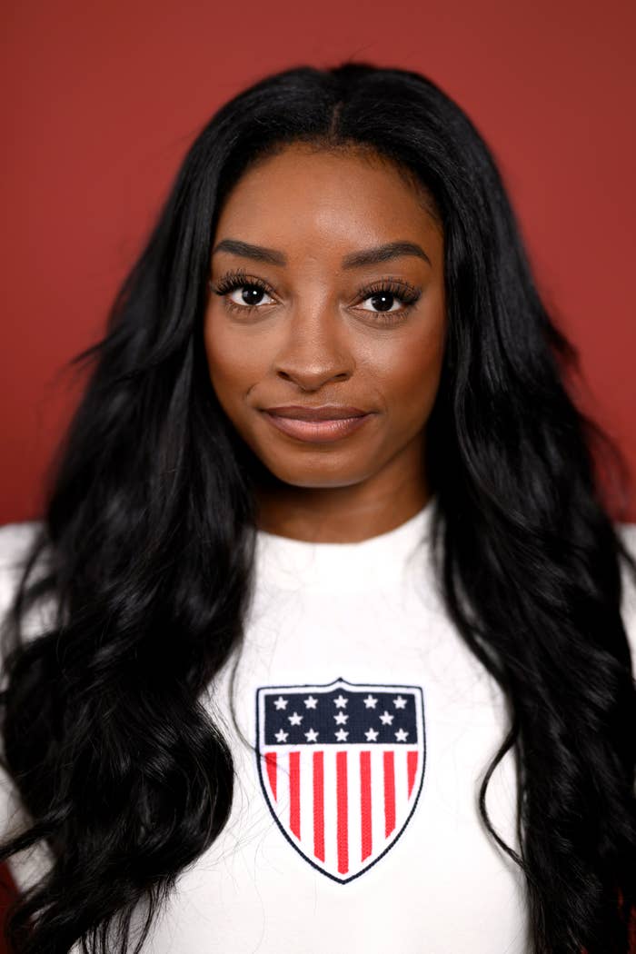 Simone Biles with long hair poses in a top featuring a USA flag patch