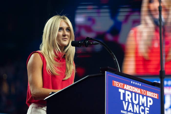 Riley Gaines speaks at a podium during a Trump rally, wearing a sleeveless top and pants