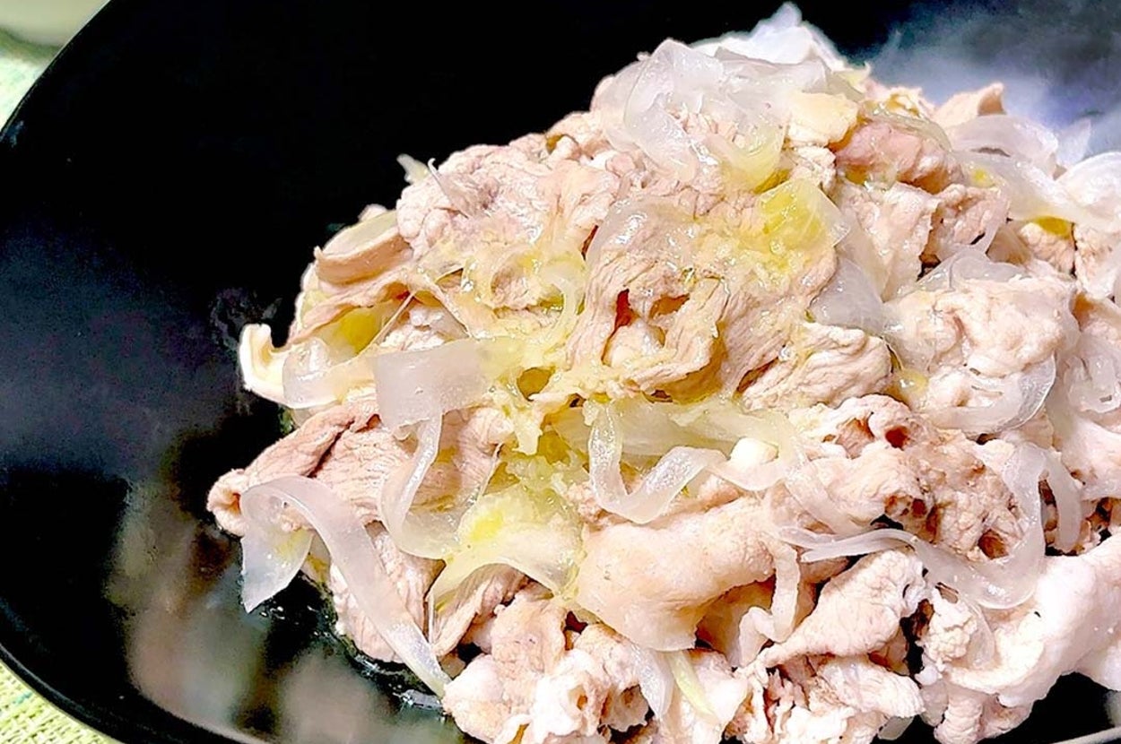 黒い皿に盛られた薄切り肉と玉ねぎの料理。脇に小皿に入ったソース。