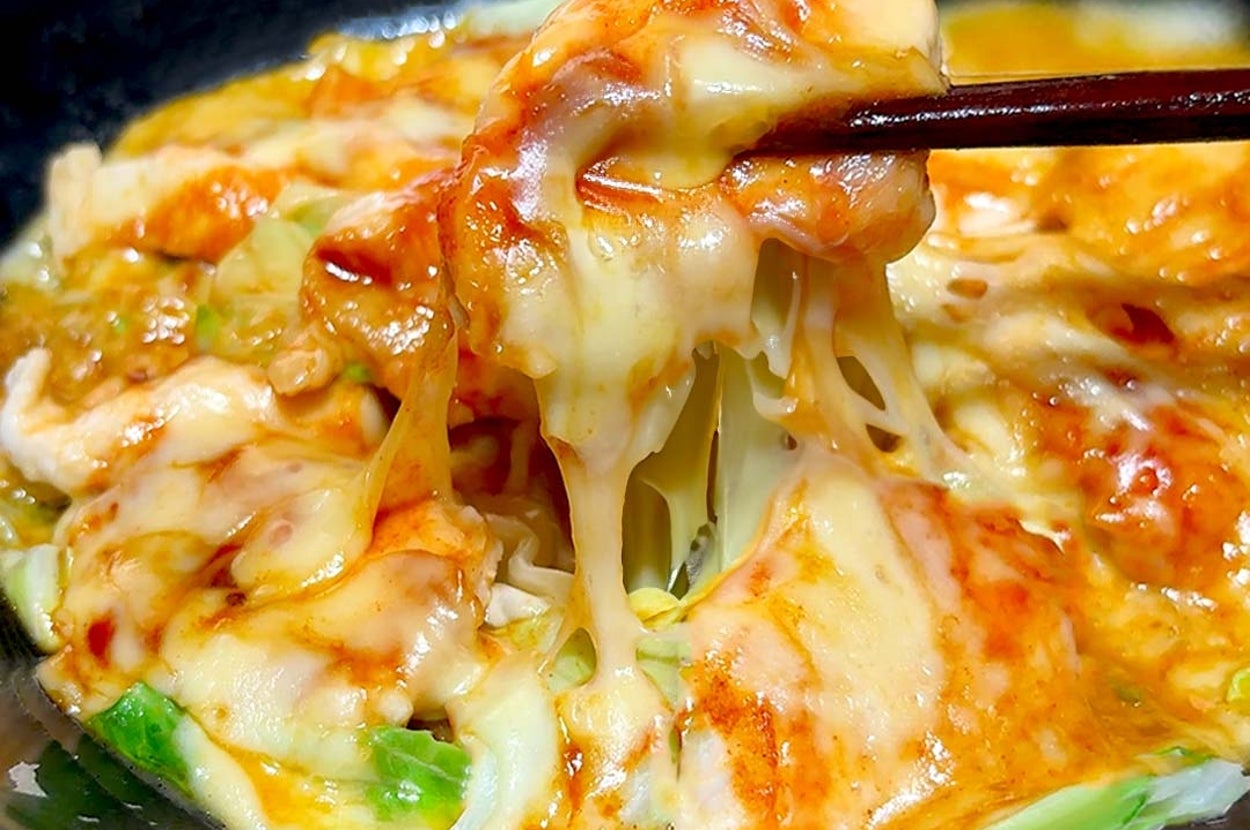 とろけるチーズがたっぷりかかった具材を箸ですくっている料理のクローズアップ。