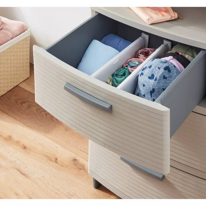 Open dresser drawer with organized compartments holding rolled shirts and underwear, illustrating neat retention solutions for a buying article