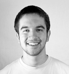 Smiling person facing the camera, wearing a plain T-shirt in a simple portrait setting