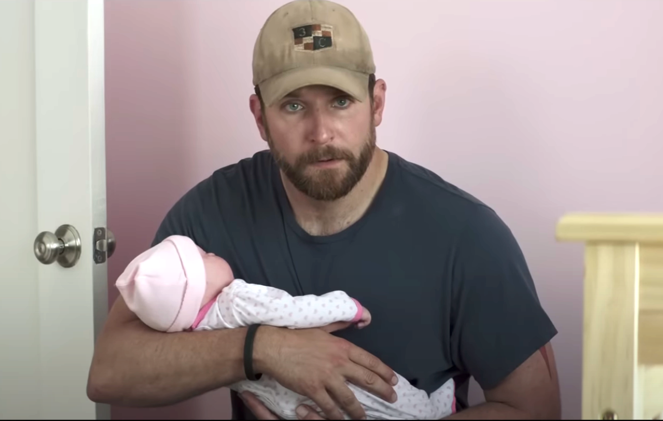 Kyle holding a baby that's obviously a doll