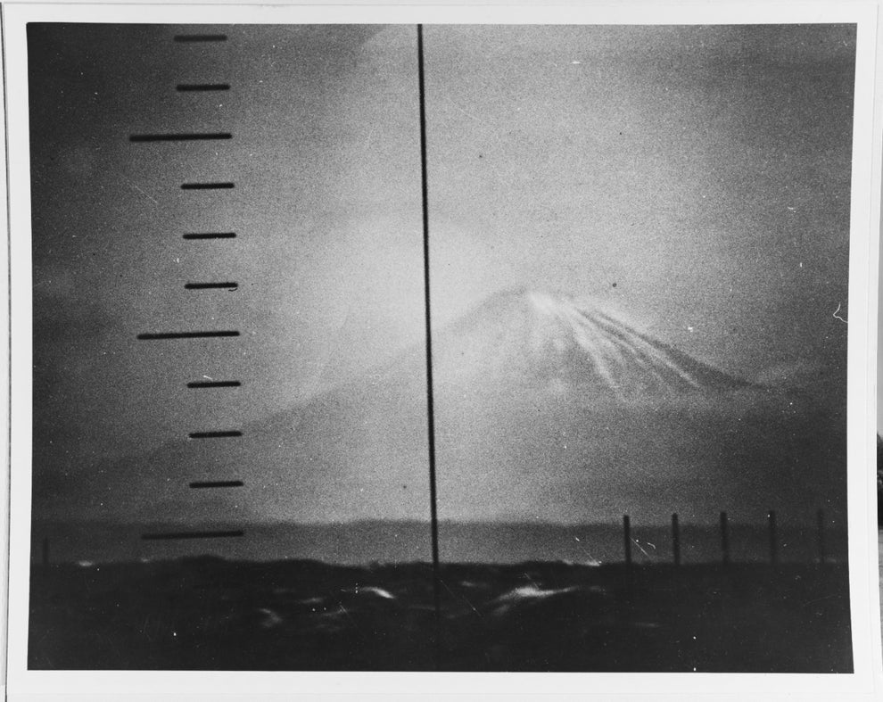 Blurry vintage photo of a mountain, possibly Fuji, with measurement lines in the foreground, creating a sense of scientific observation or survey