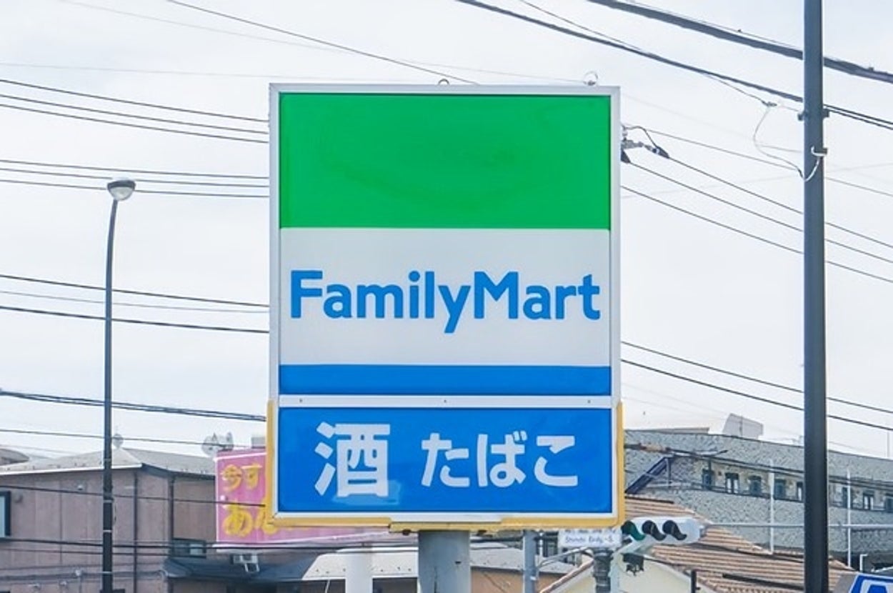 ファミリーマートの看板に「酒 たばこ」と表示。建物や電線が背景に見える。