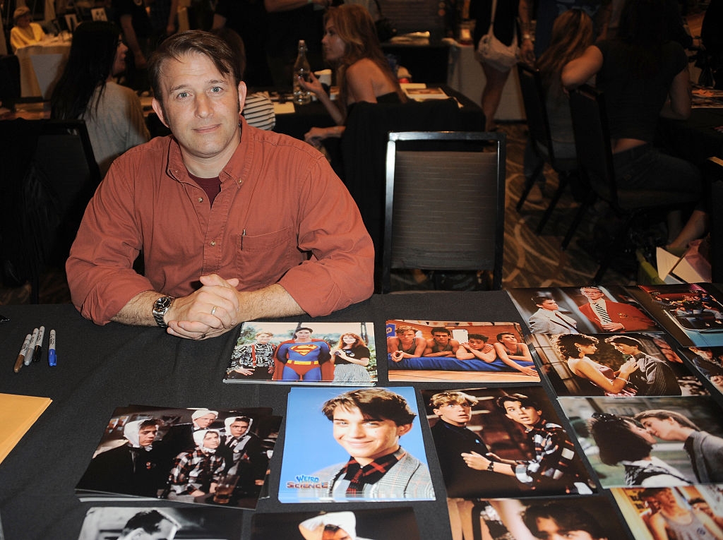 Person sitting at a table with various signed photos, some showing scenes from TV and movies