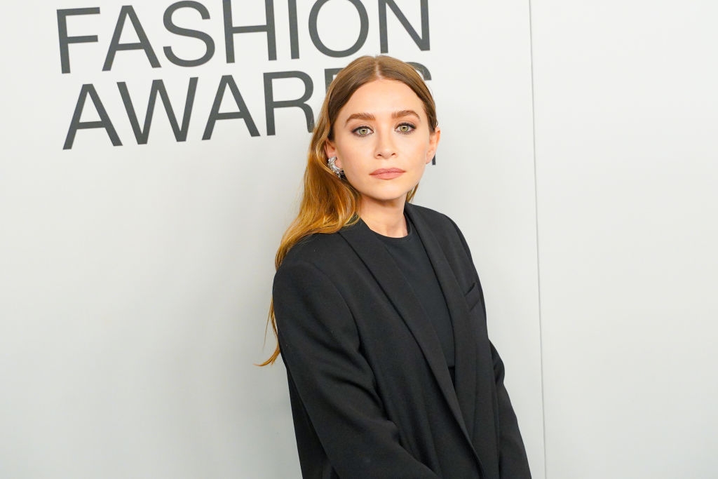 Person in a stylish black blazer with statement earrings at a fashion awards event