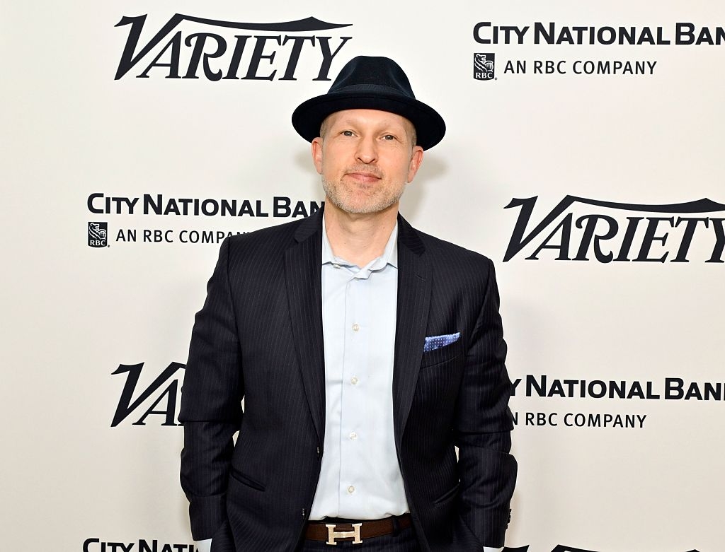 A person wearing a dark fedora and pinstripe suit stands in front of a backdrop with Variety and City National Bank logos