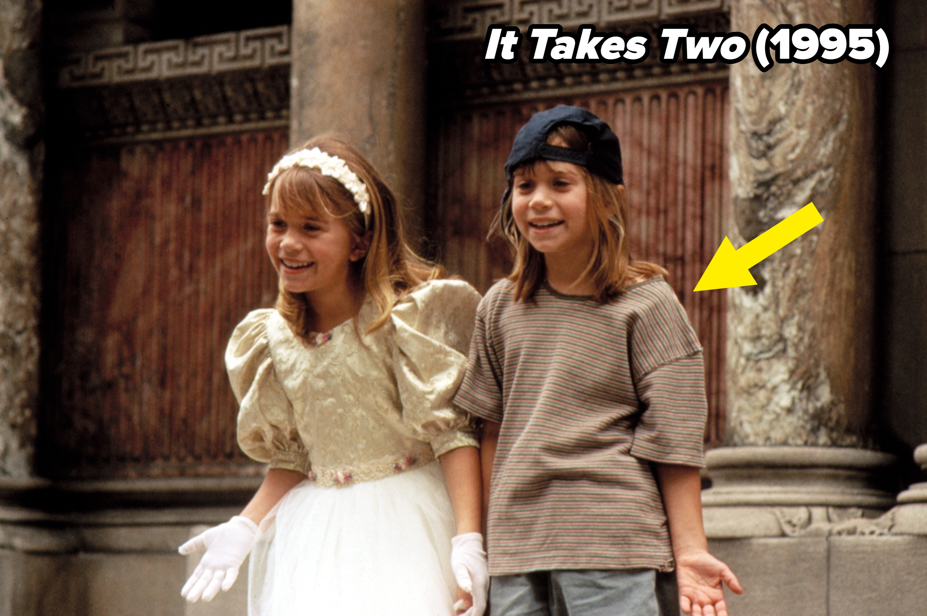 Two children stand smiling. One wears a fancy dress with a headband and gloves, the other is in casual clothes and a backwards cap