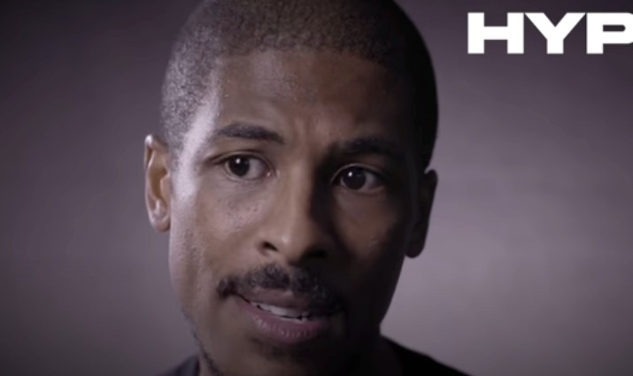 A person is speaking with a focused expression against a plain background, with the word &quot;HYPE&quot; visible