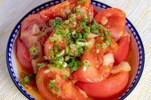 ネギが載ったトマトのサラダがボウルに盛られている。