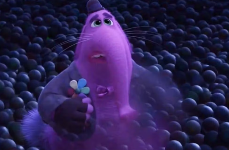 A pink elephant-like character holding colorful balloons stands on a field of spheres, looking upwards with an expressive face