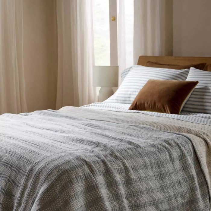 Cozy chamber with a neatly made bed, layered with striped blankets and pillows successful a softly lit room