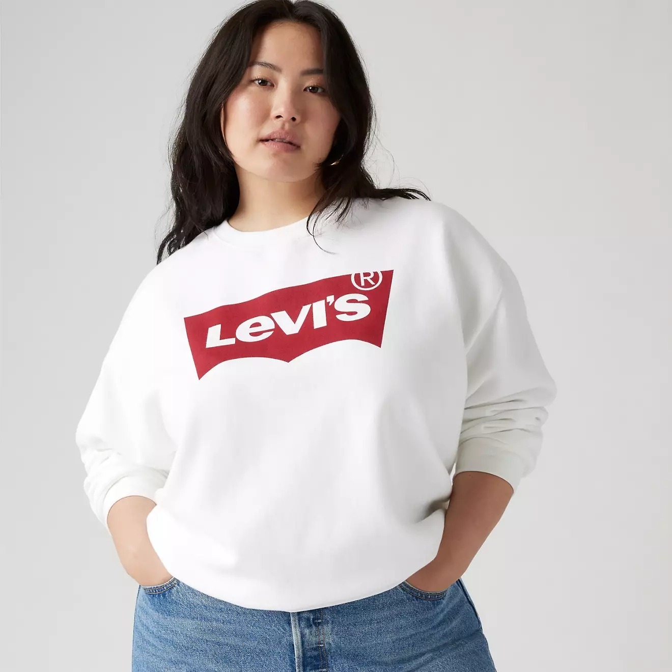 Person wearing a Levi's logo sweatshirt and blue jeans, standing confidently