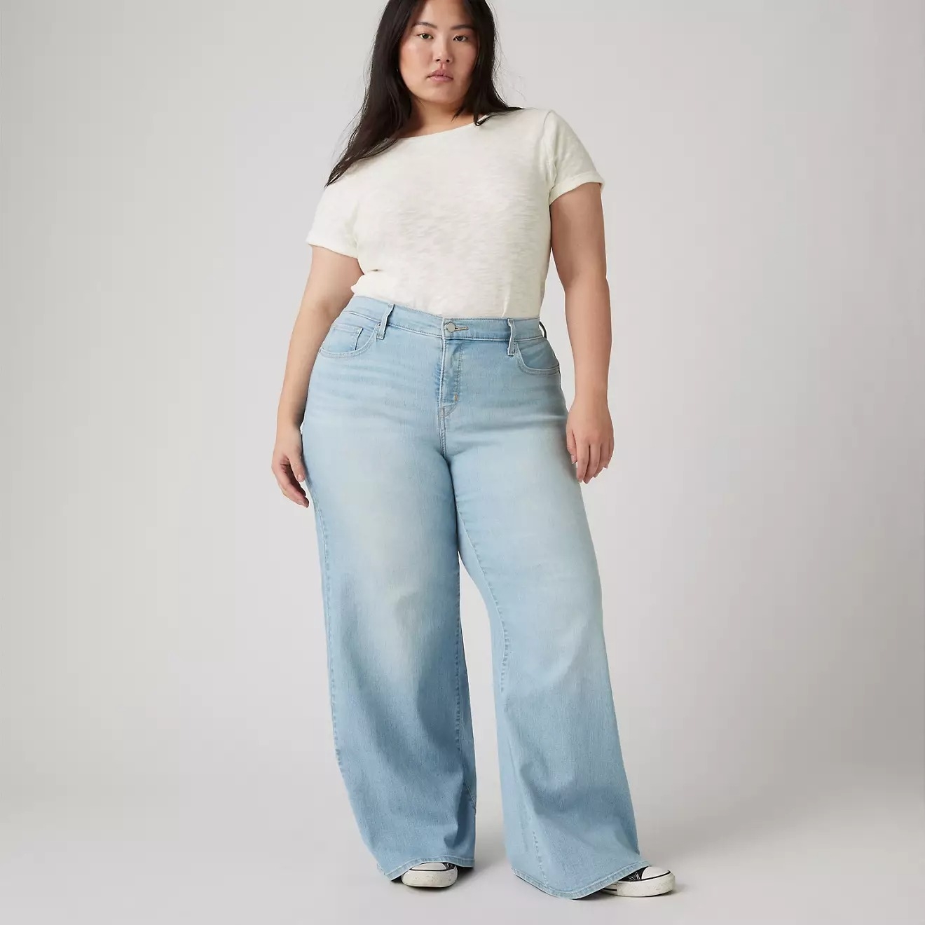 Person wearing wide-leg jeans and a plain t-shirt, standing in a neutral pose, popular for casual fashion shopping articles