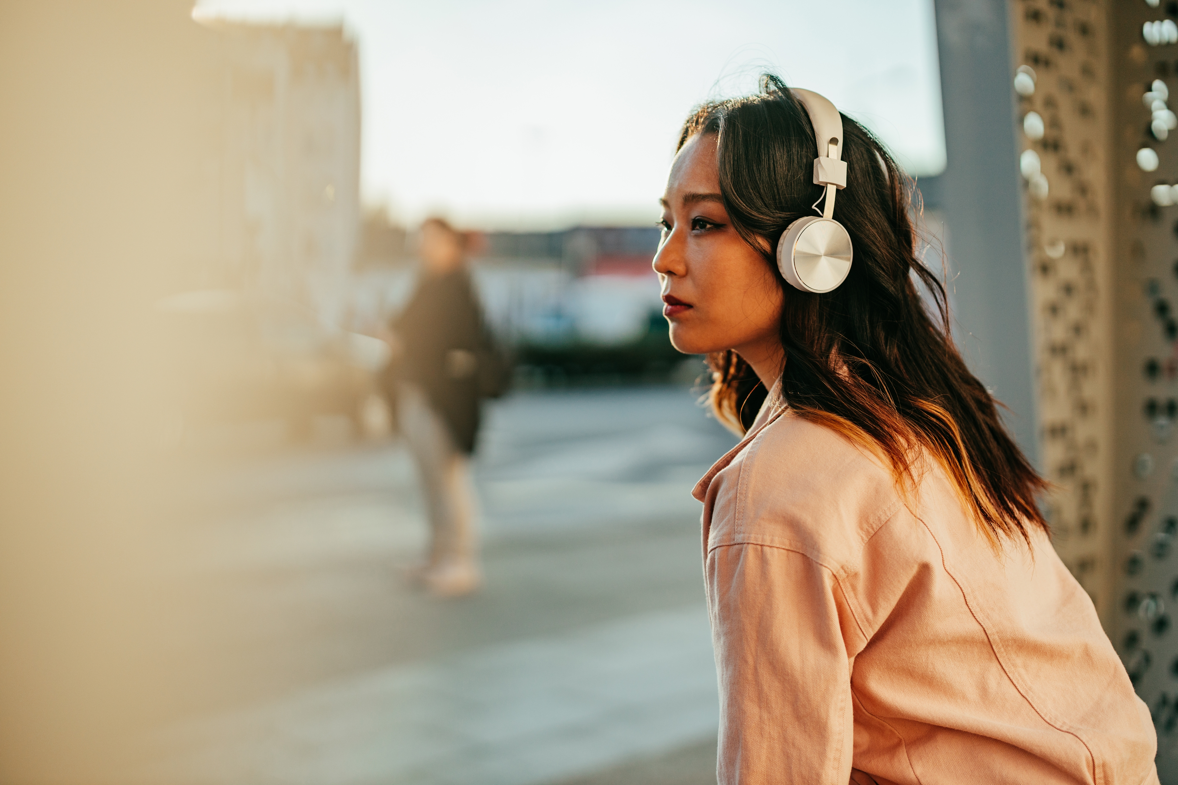 Person som har hodetelefoner, ser gjennomtenkt ut mens han sitter utendørs. Bakgrunnen er uskarpt, med fokus på den enkelte å nyte musikk eller lydinnhold