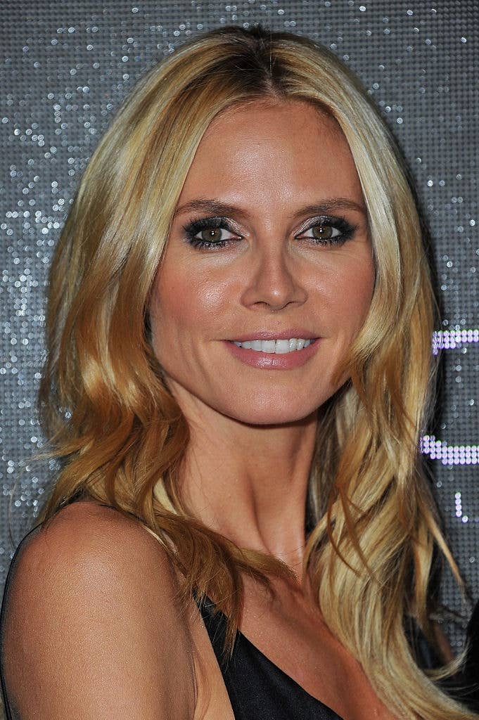 A person with long blonde hair in a sleek evening gown smiles at a glamorous event