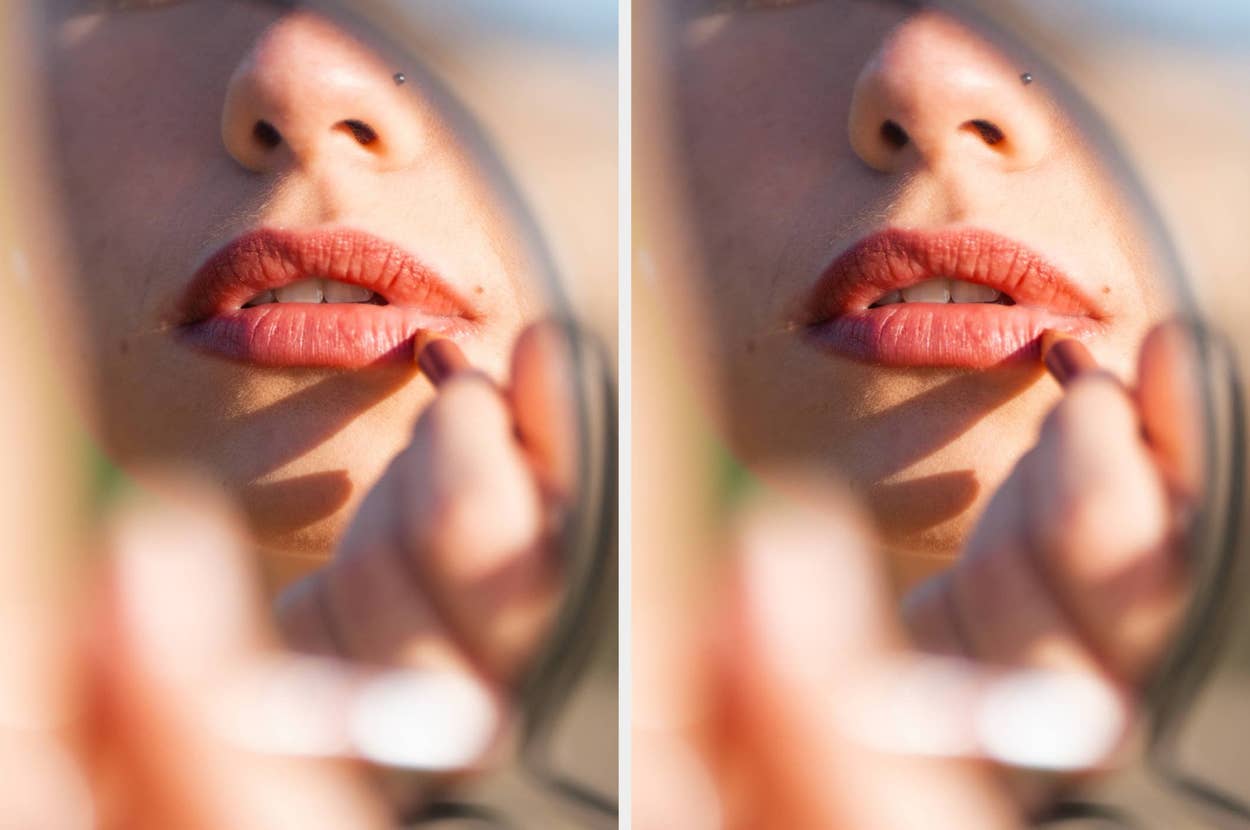 Close-up of a person applying lipstick, reflected in a handheld mirror