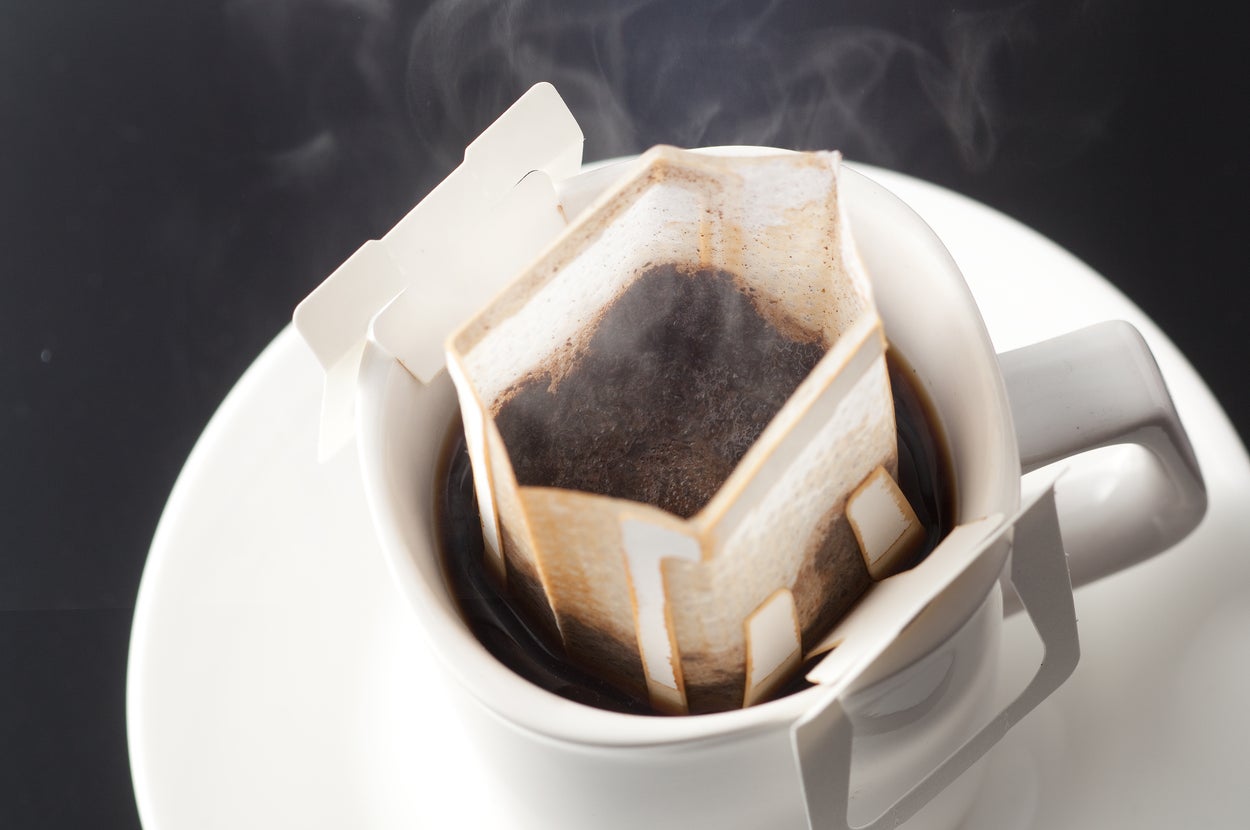 カップにセットされたドリップコーヒーのフィルターから蒸気が立ち上る様子。