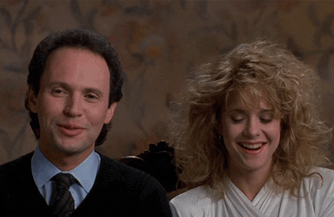 A man and woman smile and laugh together, sitting closely. The scene is from "When Harry Met Sally," promoted in connection with Hulu