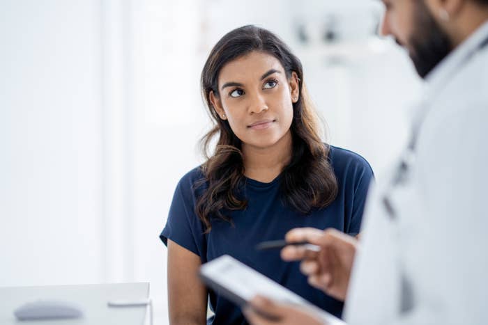 Woman attentively listens to doctor holding a tablet during a medical consultation
