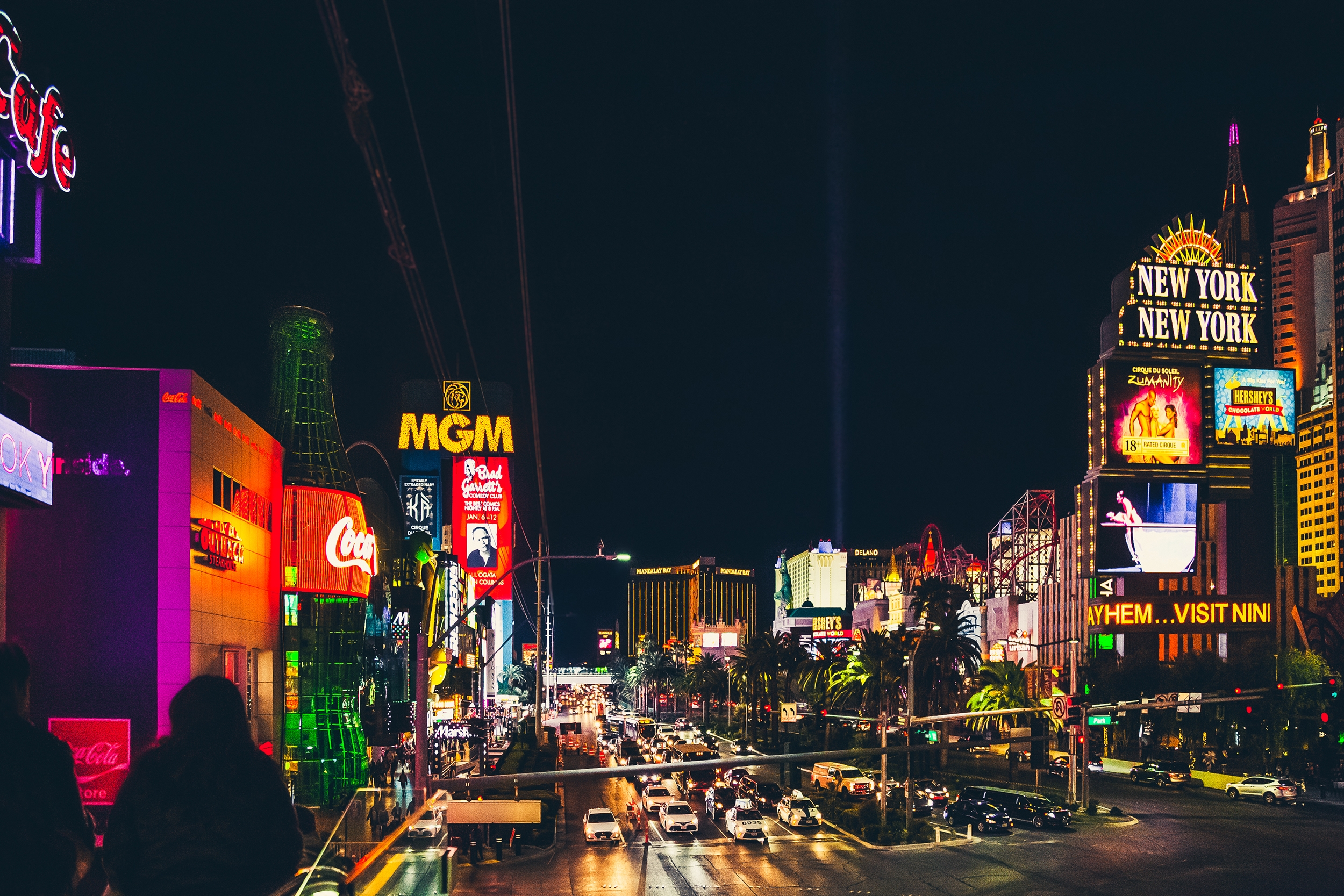 A vibrant view of Las Vegas Strip at night, showcasing illuminated signs of famous hotels and casinos, with bustling street traffic below