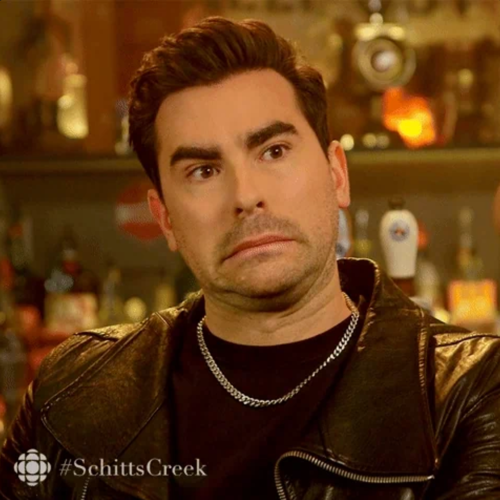 Person making an awkward expression in a bar, dressed in a leather jacket and chain necklace. Text on the image reads &quot;#SchittsCreek&quot;
