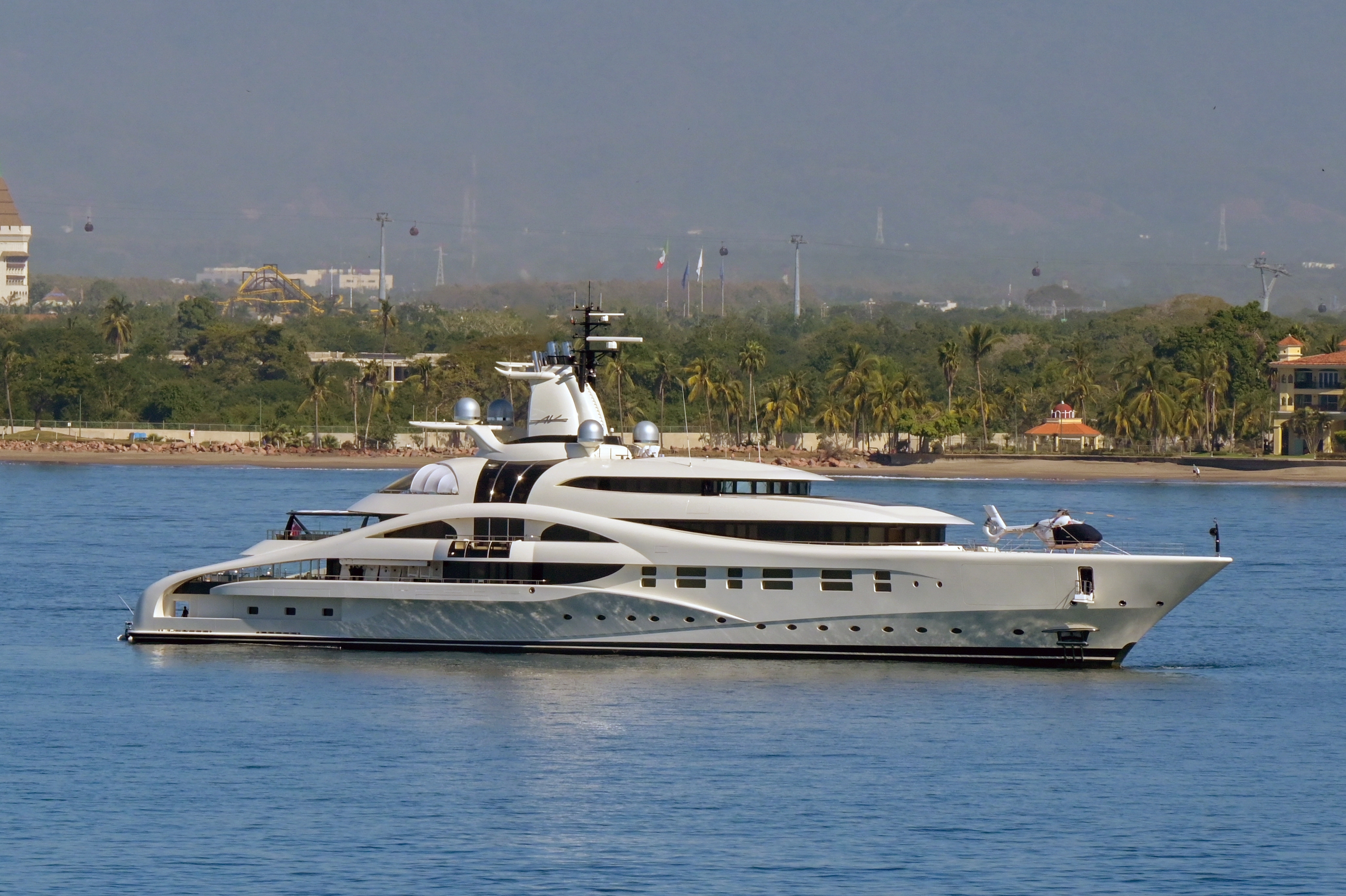 Luxury yacht cruising on calm waters with a scenic shoreline and trees in the background