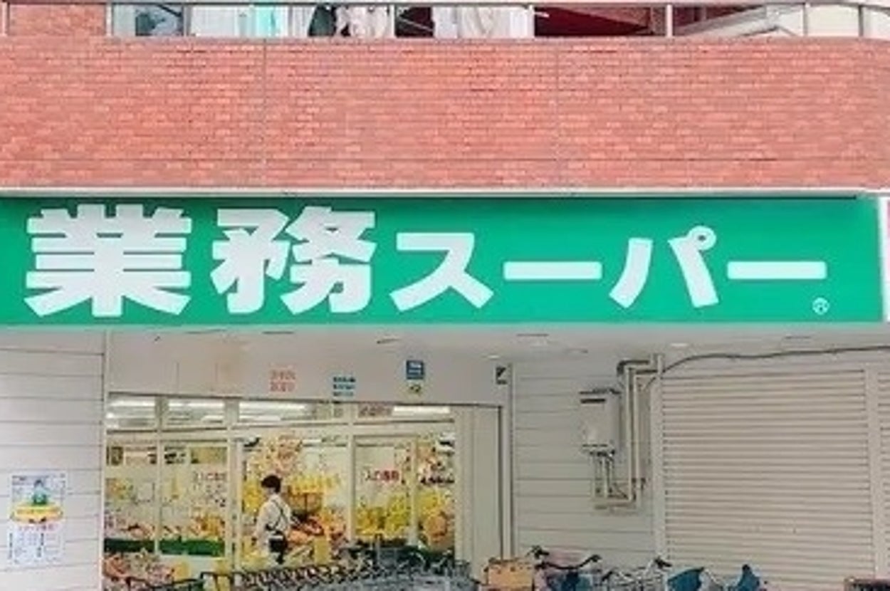 業務スーパーの外観。多数の自転車が駐輪され、人々が出入りしている様子が見える。