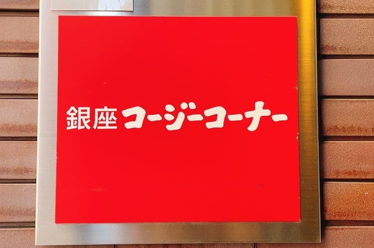 Sign on a brick wall that says “Ginza Cozy Corner” in Japanese
