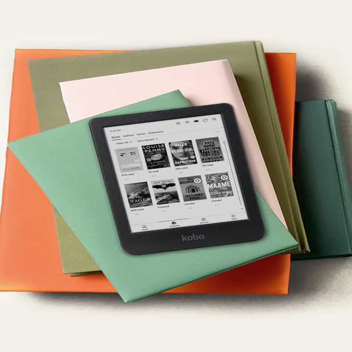 E-reader displaying nine book covers on screen, resting on a stack of various-sized closed books, suggesting reading and shopping for books