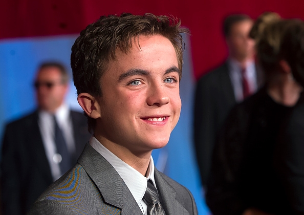 Frankie Muniz in a suit on a red carpet event, with blurred attendees in the background