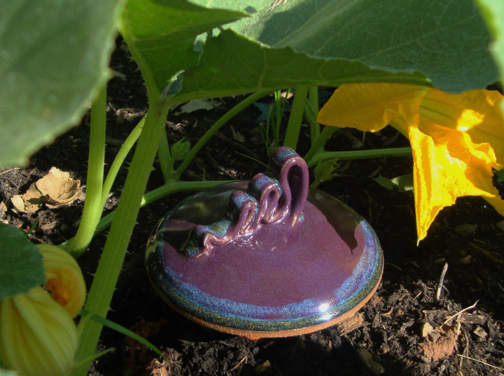 Ceramic plot  ornament resembling a purple snake among works  leaves and flowers successful  soil