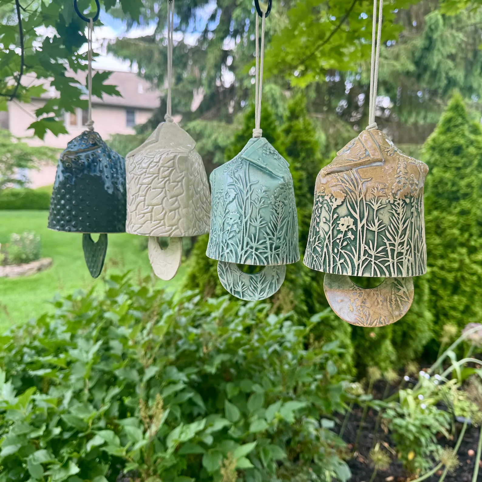 Decorative ceramic wind chimes with nature patterns hang outdoors