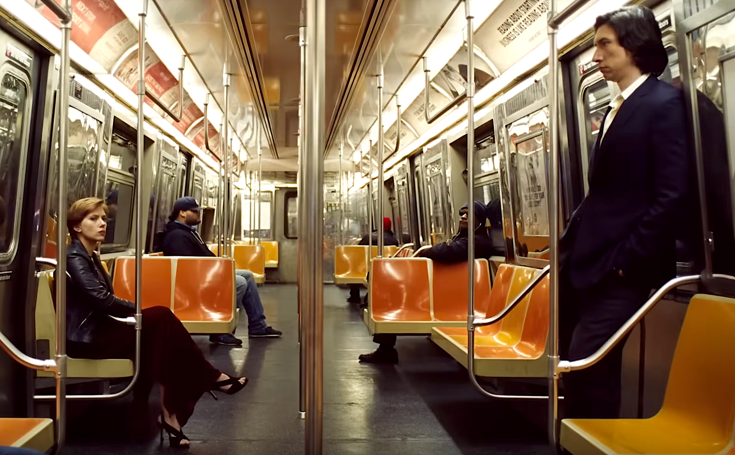Two people sit on opposite sides of an empty subway car, each appearing deep in thought
