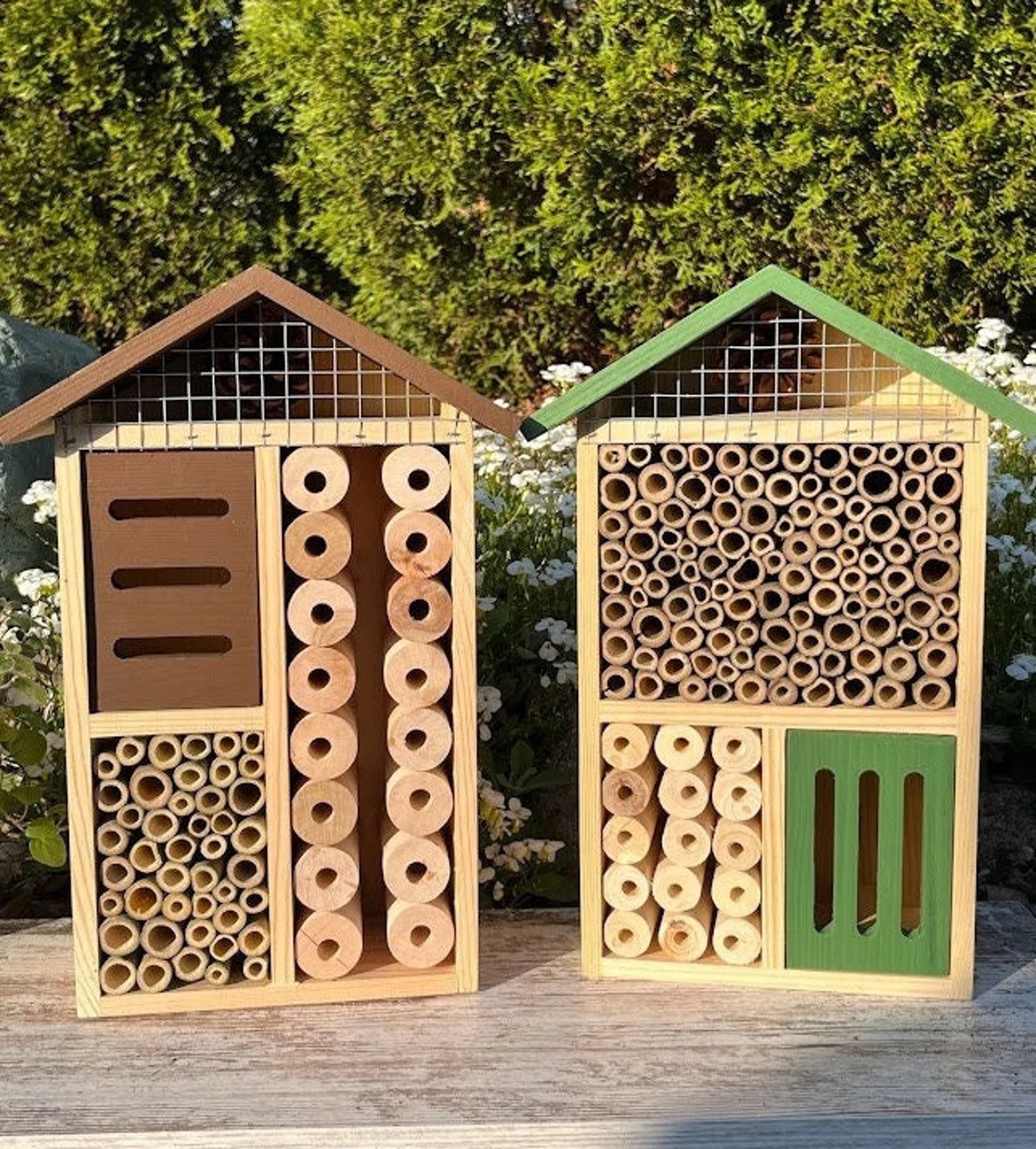 Two wooden insect hotels with natural bamboo and wood designs