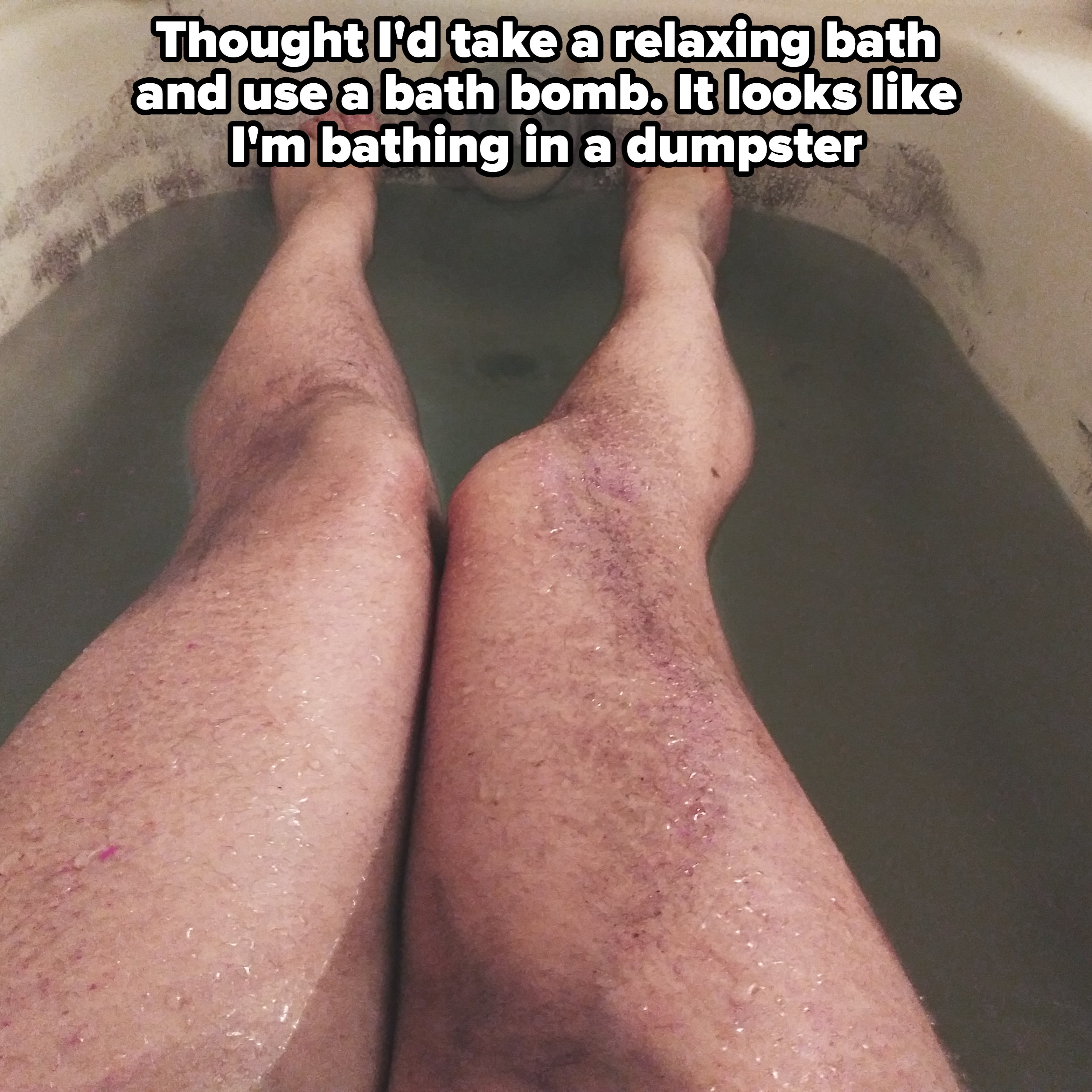 Person with hairy legs relaxing in a bathtub with murky water, showcasing a natural and relatable moment