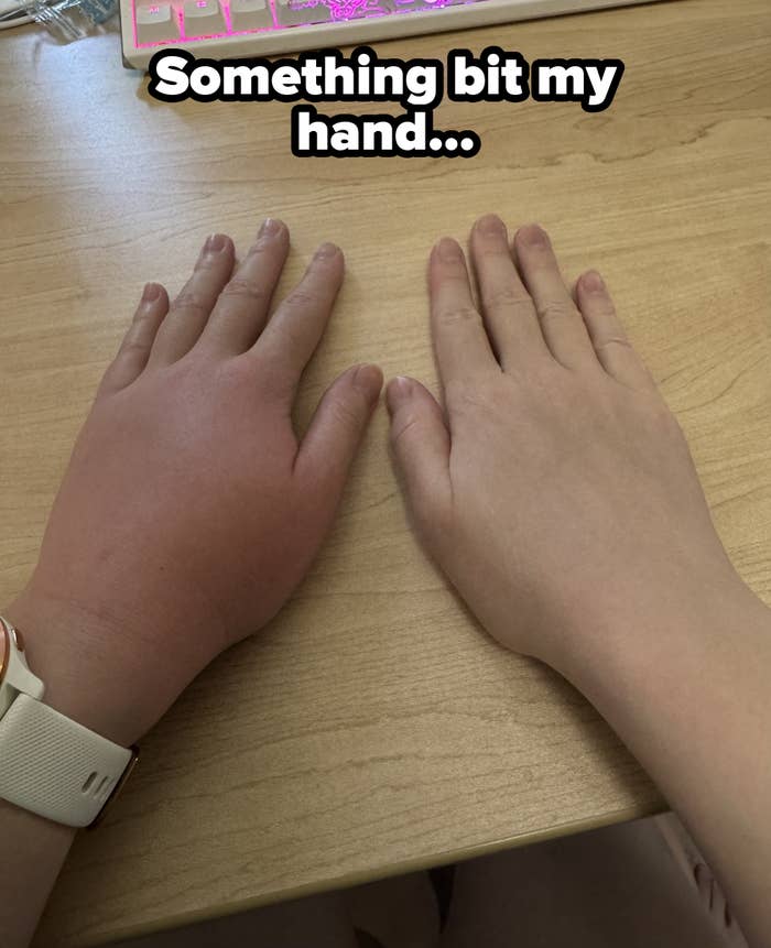 Two hands resting on a wooden table, one appears more tanned than the other. A smartwatch is worn on the left wrist
