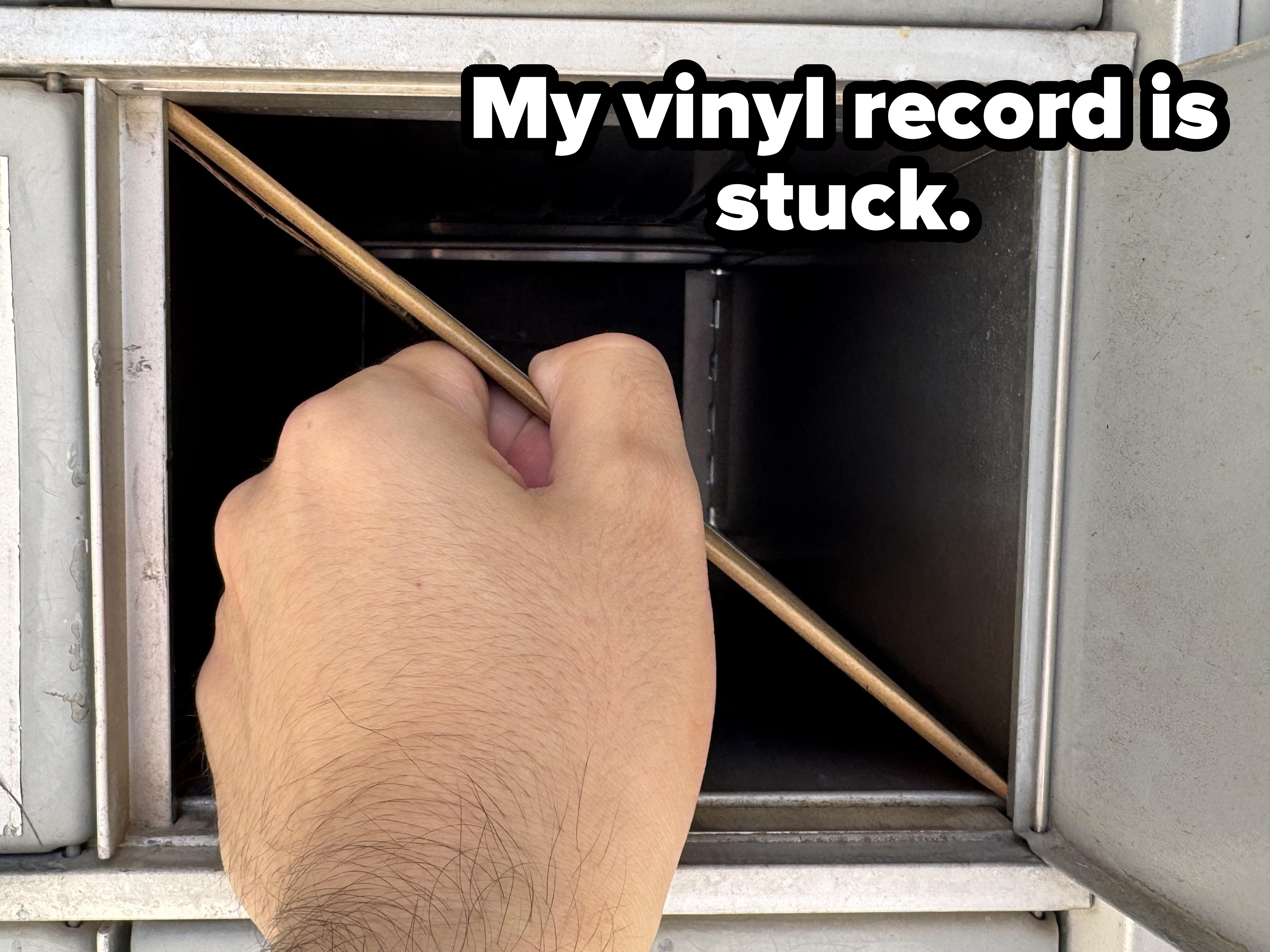 A hand is inserting a letter into an open metal mailbox slot