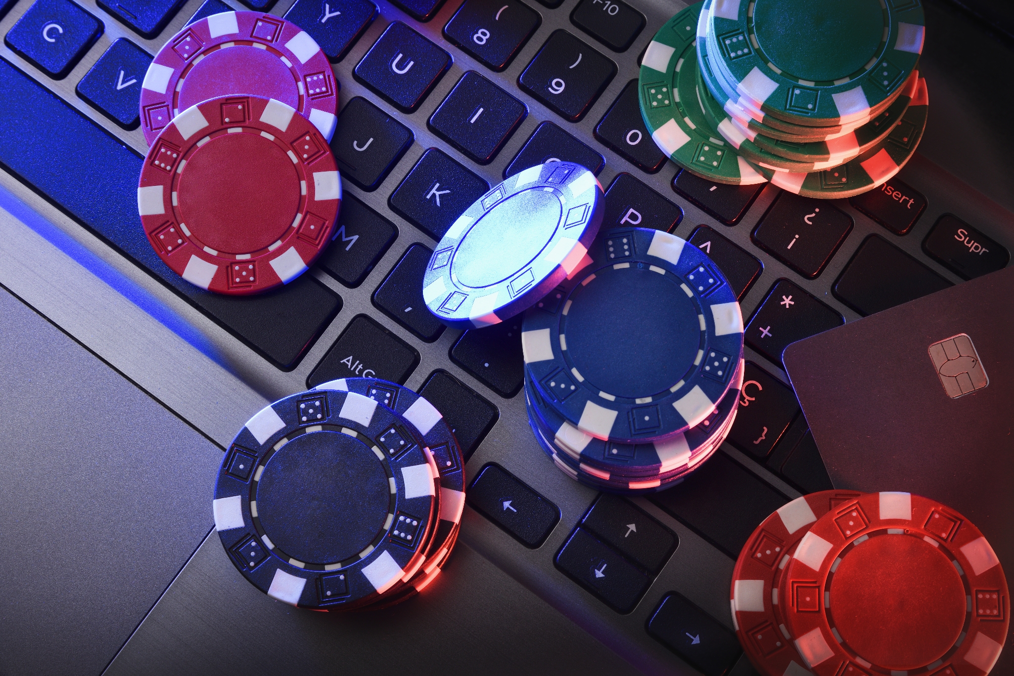 Poker chips scattered on a laptop keyboard, suggesting online gambling or gaming