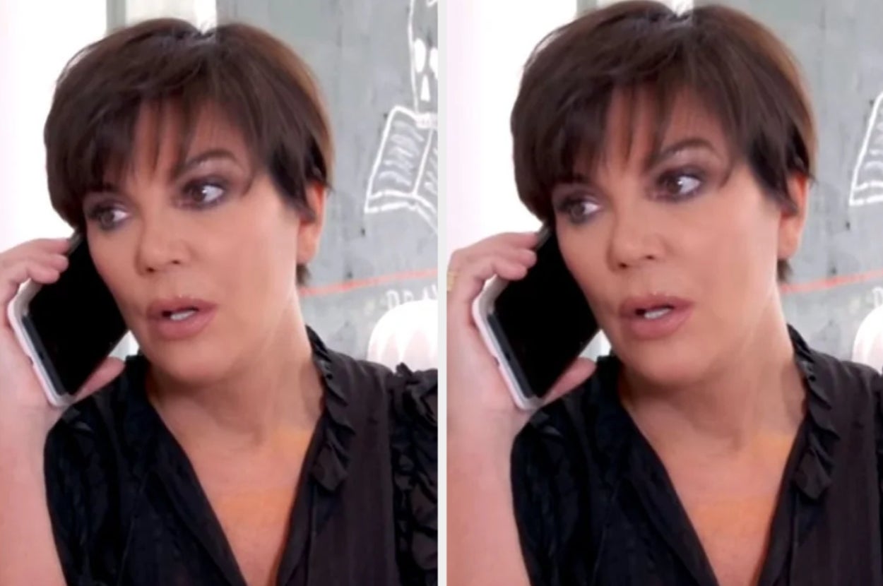 Person with short hair, wearing a black blouse, speaking on the phone. They appear attentive and engaged in the conversation