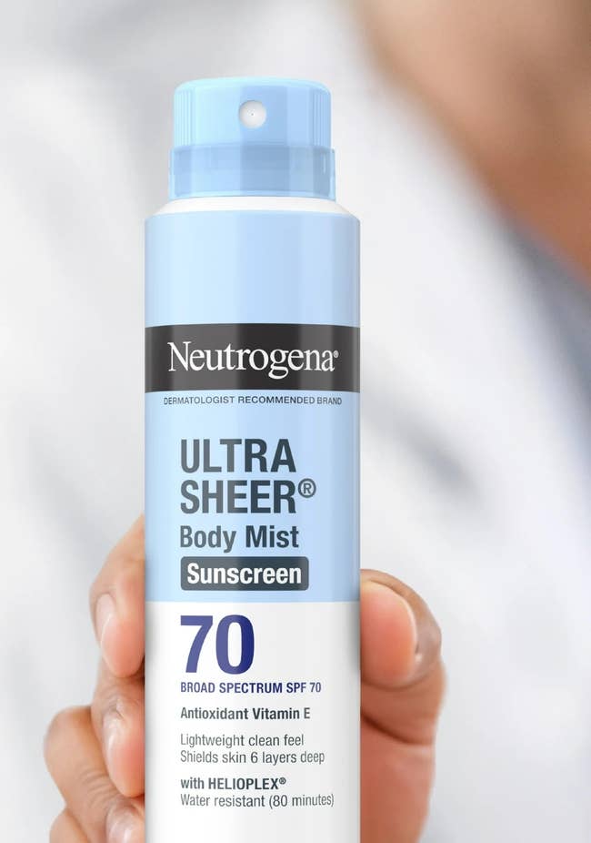Neutrogena Ultra Sheer sunscreen spray vessel held successful hand, labeled SPF 70; substance highlights it is escaped of oxybenzone and PABA