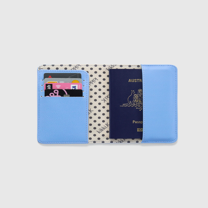 Open passport holder with polka dot lining, containing cards and a passport in an organized layout