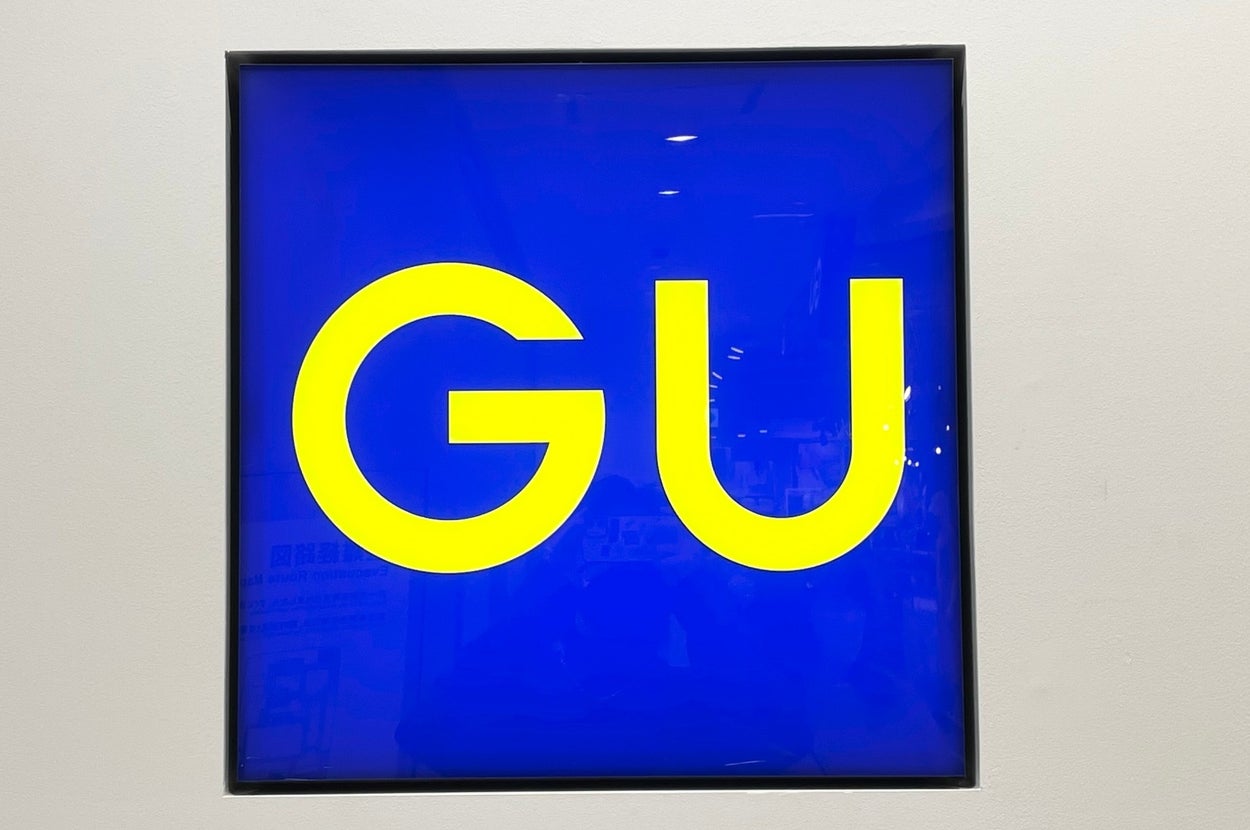 Illuminated sign with the letters "GU" displayed prominently in a square frame