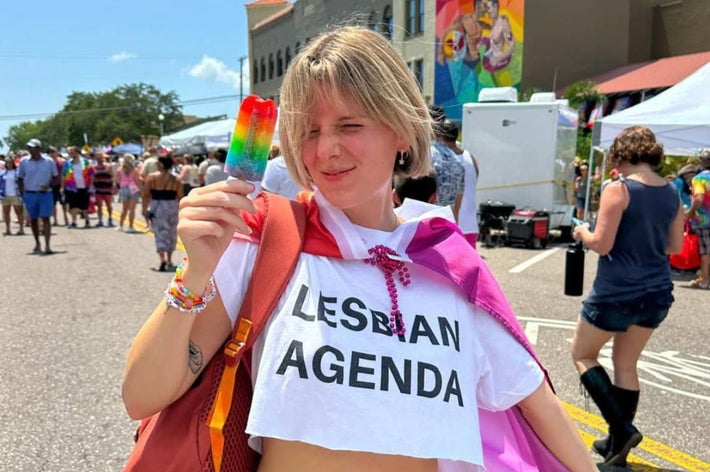 女性がバルーンを持ちながらピンクのケーキと共に座っている。彼女はキャミソールとスカートのセットを着用。