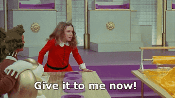 A young girl in a red outfit demands, &quot;Give it to me now!&quot; in a factory setting