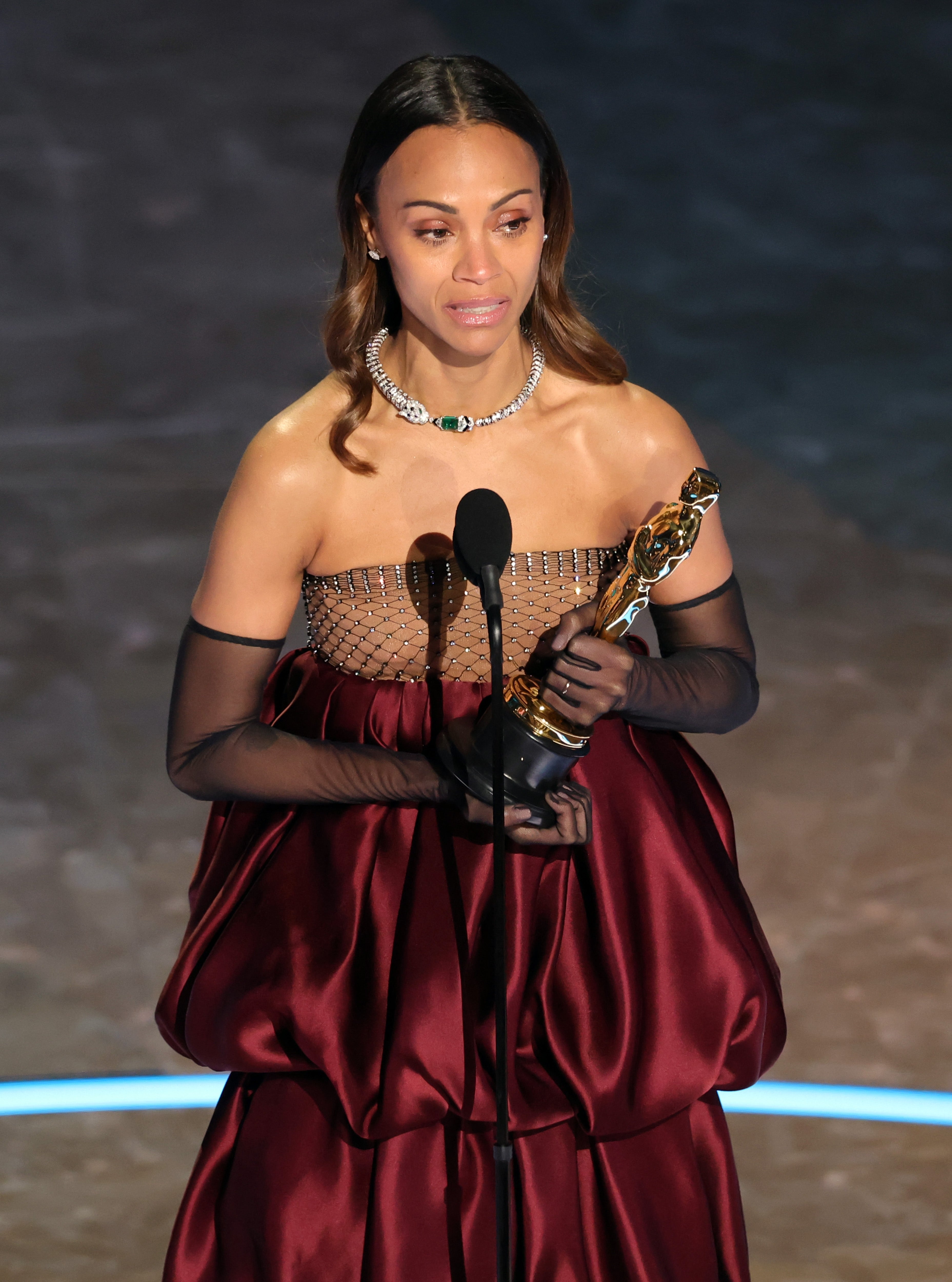 Zoe Saldaña holding an Oscar on stage