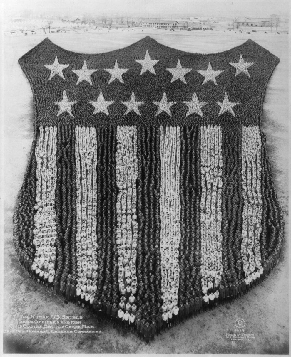 Thousands of people form a large human American flag shield design in a historic photograph