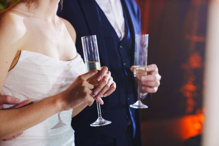Elegantly dressed newlywed couple holding champagne glasses