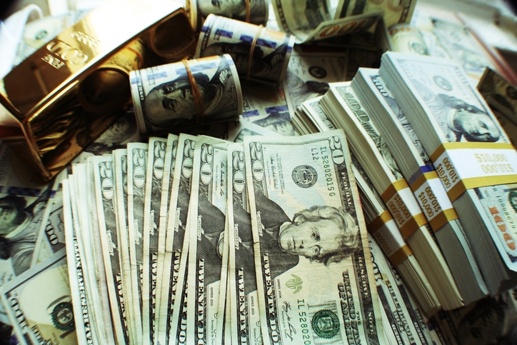 Stacks and rolls of U.S. currency with stacked gold bars, representing wealth and abundance